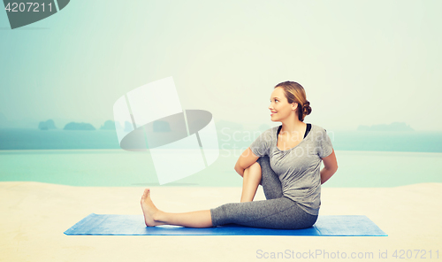 Image of woman making yoga in twist pose on mat