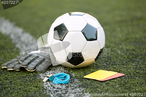 Image of ball, gloves, whistle and cards on soccer field