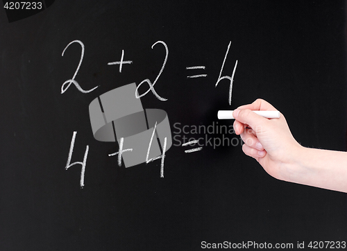Image of hand with chalk writing numbers on blackboard