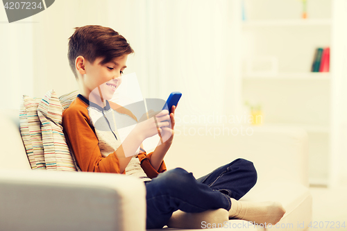 Image of boy with smartphone texting or playing at home