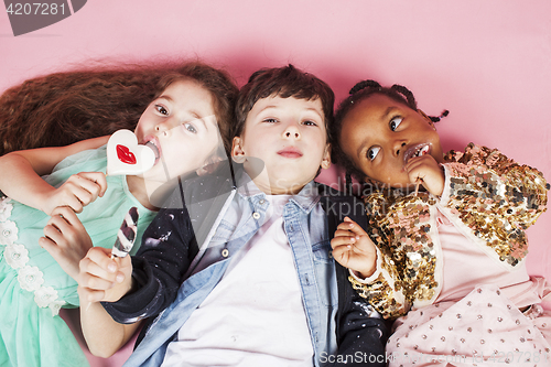 Image of lifestyle people concept: diverse nation children playing together, caucasian boy with african little girl holding candy happy smiling 