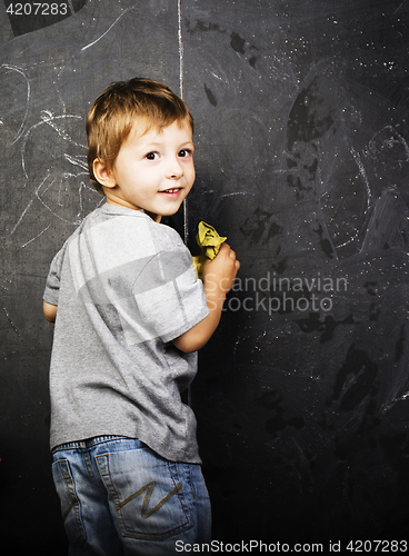 Image of little cute boy with young teacher in classroom studying at blac