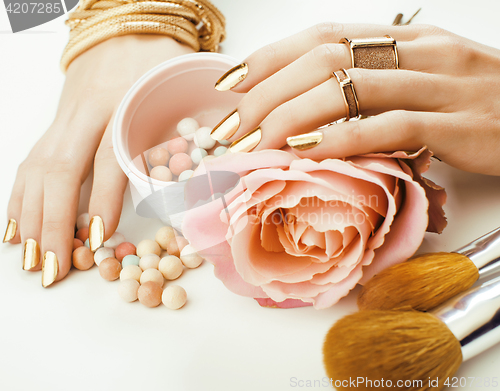 Image of woman hands with golden manicure and many rings holding brushes, makeup artist stuff stylish, pure close up