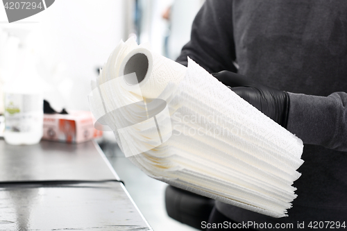 Image of A tattoo artist preparing disposable paper towels.   Hygiene in the tattoo parlor.