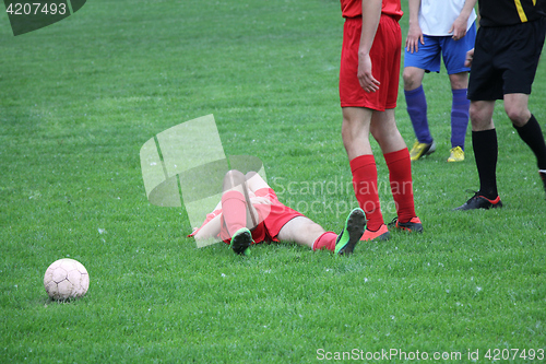Image of Injured player at the football match lying on the grass