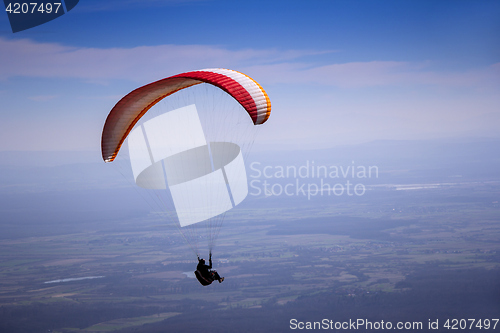 Image of Paraglider flies in the blue summer sky