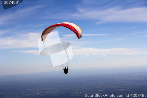 Image of Paraglider flies in the blue summer sky