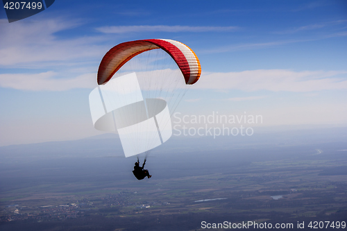 Image of Paraglider flies in the blue summer sky