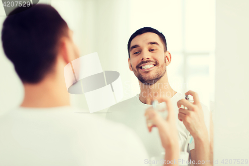 Image of man with perfume looking to mirror at bathroom