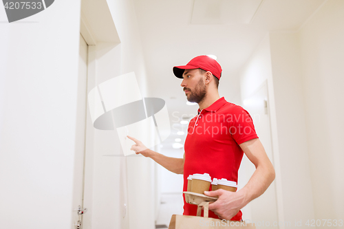 Image of delivery man with coffee and food ringing doorbell