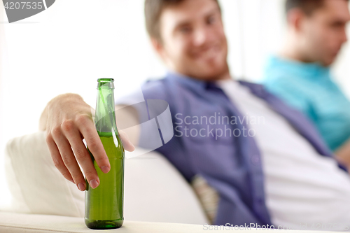 Image of men with beer bottles sitting on sofa at home