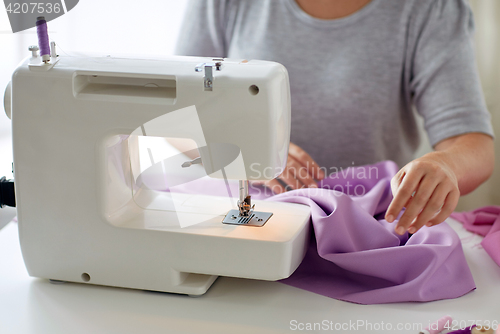 Image of tailor woman with sewing machine stitching fabric