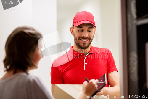 Image of delivery man with box and tablet pc at customer