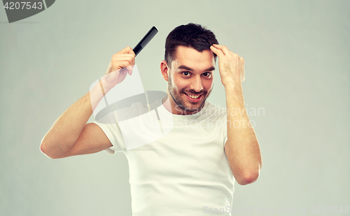 Image of happy man brushing hair with comb over gray