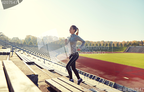 Image of happy young woman running upstairs on stadium