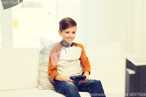 Image of happy boy with joystick playing video game at home