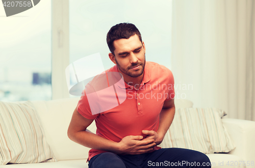 Image of unhappy man suffering from stomach ache at home