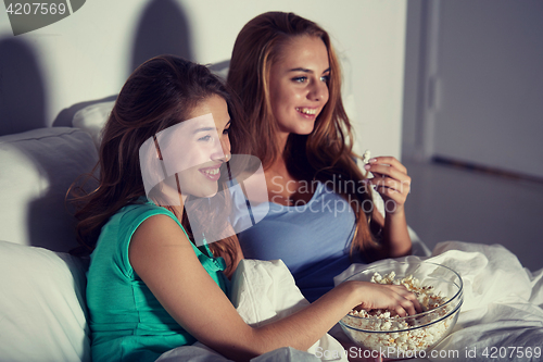 Image of happy friends with popcorn and watching tv at home