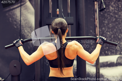 Image of woman flexing muscles on cable machine in gym