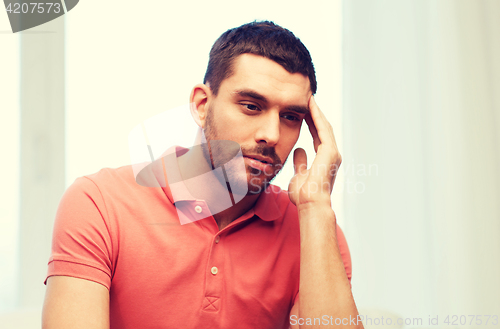 Image of unhappy man suffering from headache at home