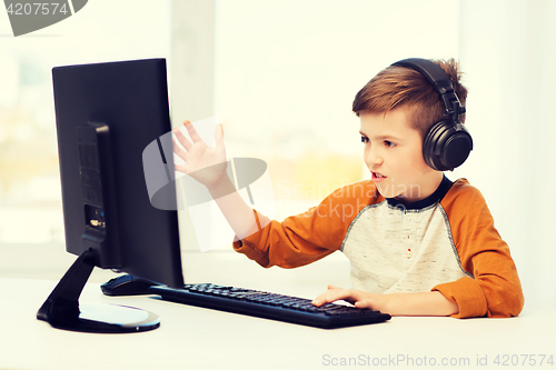 Image of boy with computer and headphones at home