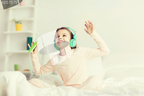 Image of girl sitting on bed with smartphone and headphones