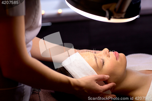 Image of beautician doing face massage to woman at spa