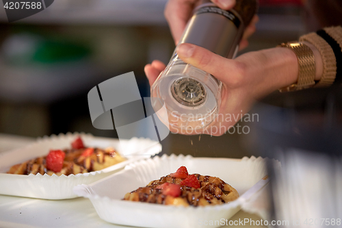 Image of close up of cook hands spicing waffle