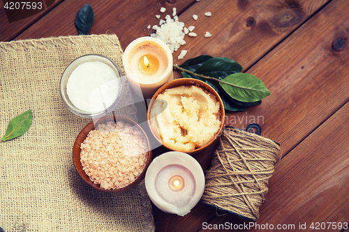 Image of close up of natural body scrub and candles on wood