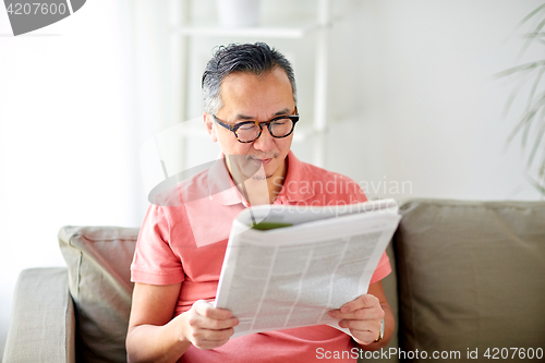 Image of happy man in glasses reading newspaper at home