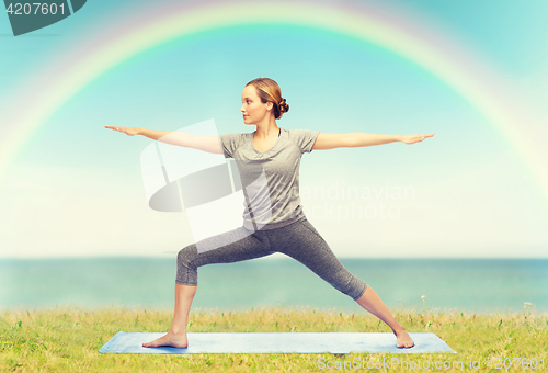 Image of woman making yoga warrior pose on mat