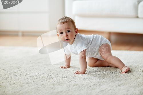 Image of little baby in diaper crawling on floor at home