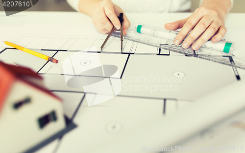 Image of close up of hands with compass measuring blueprint