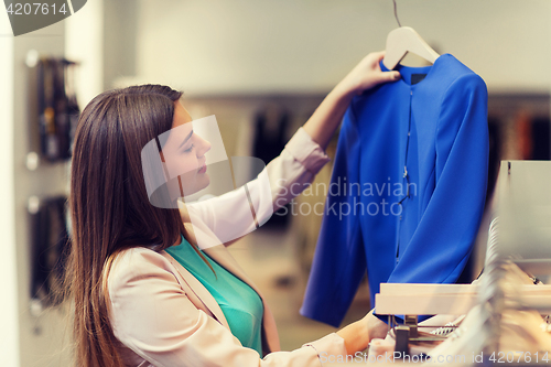 Image of happy young woman choosing clothes in mall