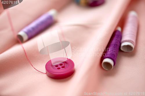 Image of sewing buttons, spools of thread and cloth