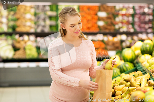 Image of pregnant woman with bag buying pears at grocery