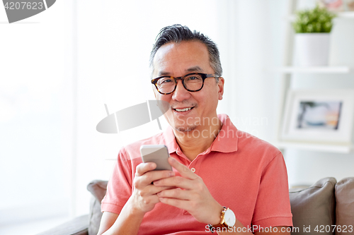 Image of man with smartphone sitting on sofa at home