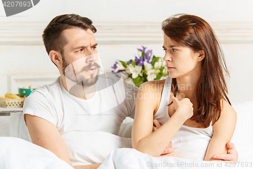 Image of Young adult heterosexual couple lying on bed in bedroom