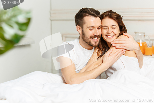 Image of Young adult heterosexual couple lying on bed in bedroom