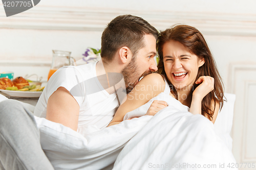 Image of Young adult heterosexual couple lying on bed in bedroom