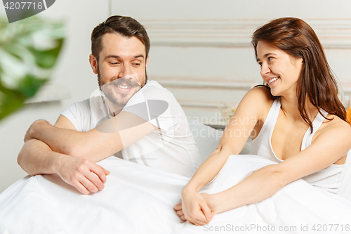 Image of Young adult heterosexual couple lying on bed in bedroom