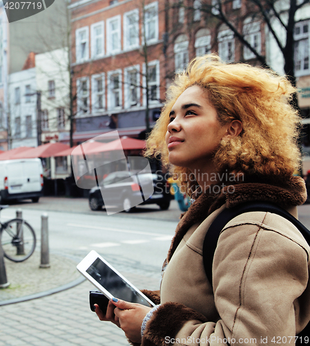 Image of young pretty african american girl with curly hair making photo on a tablet, lifestyle people concept, tourist in european german city