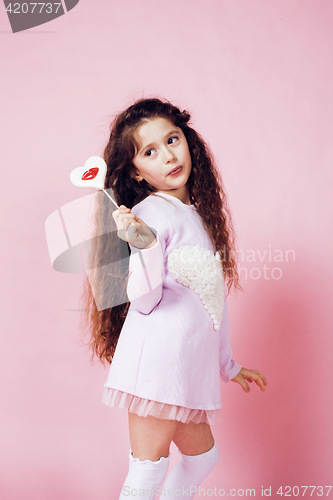 Image of little cute girl with candy on pink background posing emotional, lifestyle people concept 