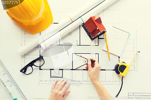 Image of close up of hands with compass measuring blueprint