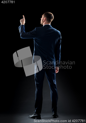 Image of businessman in suit touching something invisible