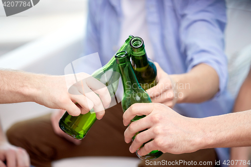 Image of close up of friends clinking beer bottles at home
