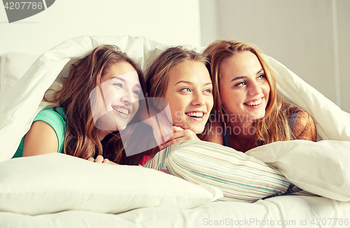 Image of happy young women in bed at home pajama party