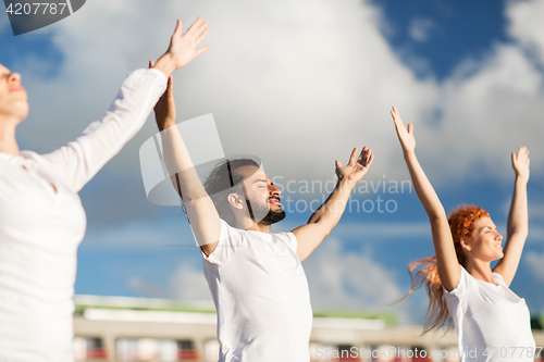 Image of group of people making yoga exercises outdoors