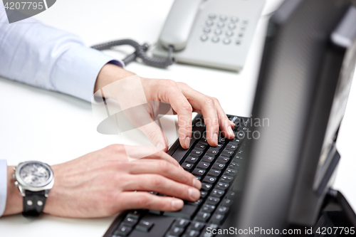 Image of close up of male hands typing on computer keyboard