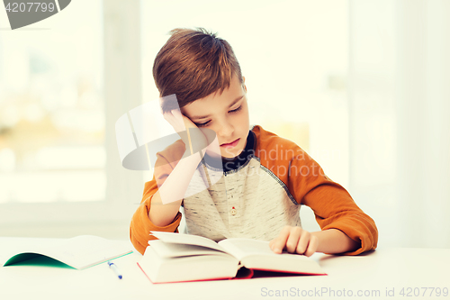 Image of student boy reading book or textbook at home